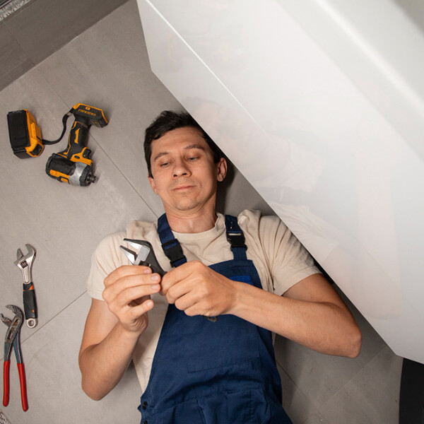 Plomero acostado en el piso preparando una llave para seguir trabajando