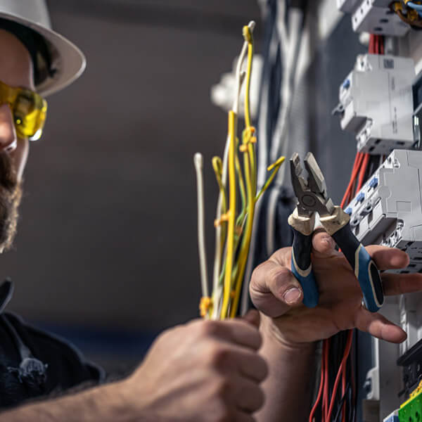 Hombre de barba sosteniendo varios cables al reparar una emergencia