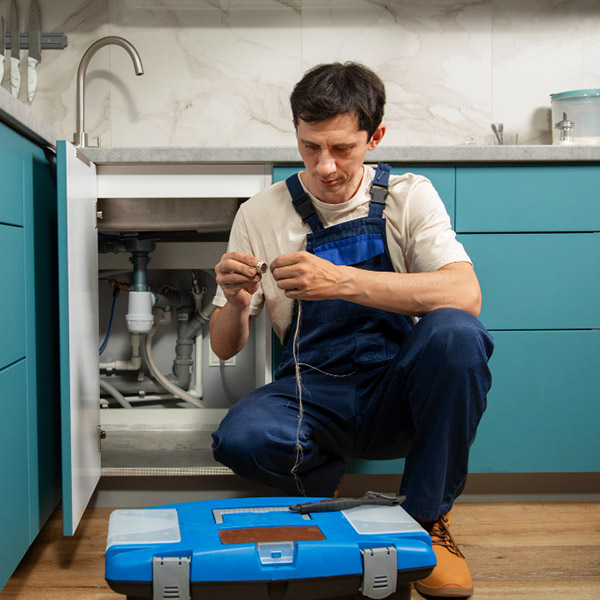 Profesional de fontanería en cuclillas en una cocina realizando una reparación