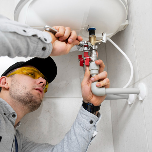 Hombre ajustando con una llave una tubería para instalar un calefón en un baño