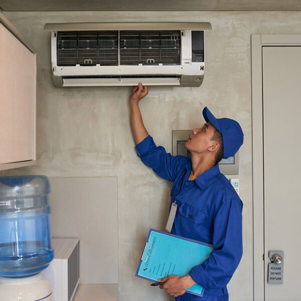 Empleado haciendo mantenimiento de aire acondicionado en la cocina de una empresa de Colonia, Uruguay