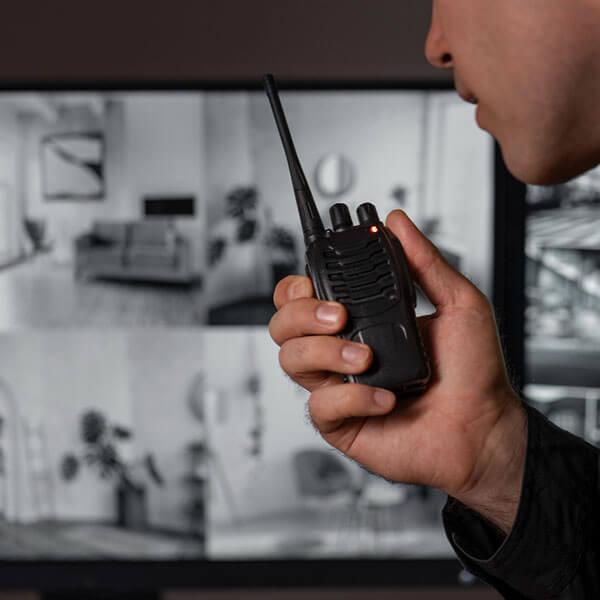Personal de seguridad y control de acceso comunicando por radiollamada algo que observa en las cámaras